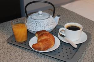 a tray with a tea pot and a croissant and a cup of coffee at Victoria by Petit Chic in Mellieħa
