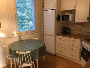 a kitchen with a table and a white refrigerator at Spacious 3 room flat with balcony at City Center in Kerava