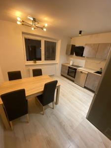 a kitchen and dining room with a wooden table and chairs at Apartman M&M in Žilina