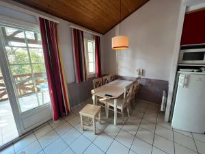eine Küche mit Tisch und Stühlen und einem Kühlschrank in der Unterkunft Appartement 3 pièces 4 personnes, à Moliets et Maa, proche Golf, grand balcon et piscine in Moliets-et-Maa