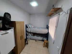 een kleine kamer met 2 bedden en een koelkast bij Quarto Deluxe em Foz piscina wifi estacionamento cozinha E AR in Foz do Iguaçu