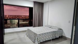 1 dormitorio con cama y ventana grande en Estúdio no 27º Andar com Vista p/ Av. Afonso Pena, en Campo Grande