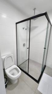 a bathroom with a toilet and a glass shower at Estúdio no 27º Andar com Vista p/ Av. Afonso Pena in Campo Grande