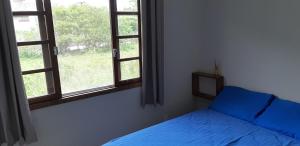 a bedroom with a blue bed and two windows at Aconchego em Floripa in Florianópolis