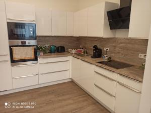 a kitchen with white cabinets and a stove top oven at Adessa Apartment in Bad Mergentheim