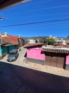 a car parked next to a pink building on a street at Happy Place in San Cristóbal de Las Casas