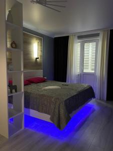 Un dormitorio con una cama con luces azules. en Бизнесс Апартаменты Центр Уральск en Oral