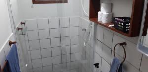 a white tiled bathroom with a shower with blue towels at Aconchego em Floripa in Florianópolis