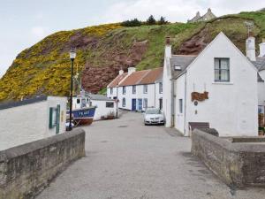 a street with houses and a car parked next to a hill at Fisherman's Cottage in Pennan in Pennan