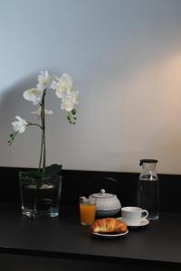 a table with a vase with a flower and a plate of croissants at Victoria by Petit Chic in Mellieħa