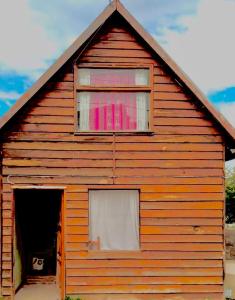 un granero de madera con ventana y puerta en La alpina de YOLI en Ushuaia