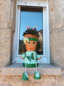 a statue of a woman with a flower pot on a window at O Cobo vacacional in A Coruña