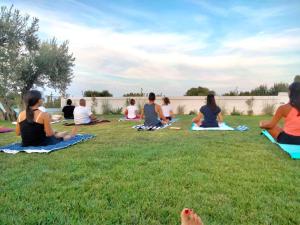 a group of people sitting in the grass practicing yoga at Tenuta Amostuni-Country House in Ostuni
