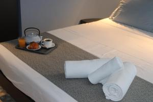 a hotel bed with a tray of food and a plate of food at Victoria by Petit Chic in Mellieħa