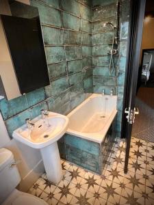 a bathroom with a sink and a tub and a toilet at Historic & Stylish Cottage in Charlton Kings +25 photos