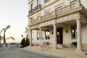 a woman walking in front of a white building at Quinta da Bella Vista - Historic Home and Farm in Sintra