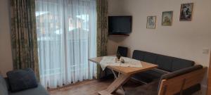 sala de estar con mesa y TV en Pension Wildental, en Sankt Martin bei Lofer