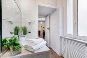 baño con lavabo con toallas y plantas en Living Rome Repubblica apartment, en Roma