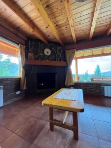 sala de estar con mesa y chimenea en Las Liebres Casa de Montaña en El Hoyo