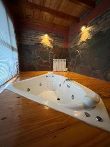 Las Liebres Casa de Montaña في الهويو: حوض استحمام في غرفة بجدار حجري +15 صورة