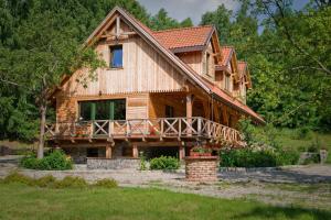 a log cabin with a wrap around porch and a deck at Uroczysko Leźno in Małe Leżno
