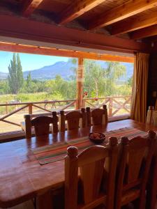 una gran mesa de madera con sillas y una gran ventana en Las Liebres Casa de Montaña en El Hoyo