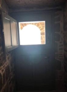 uma porta com uma janela num quarto escuro em Lemon's Cottage House, Volissos, Chios em Volissos