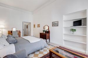 a white bedroom with a bed and a television at Living Rome Repubblica apartment in Rome