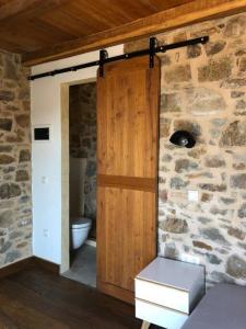 a bathroom with a wooden door and a toilet at Lemon's Cottage House, Volissos, Chios in Volissos
