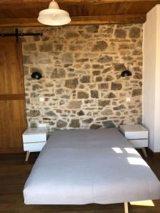 a bed in a room with a stone wall at Lemon's Cottage House, Volissos, Chios in Volissos