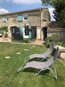 zwei Gartenstühle im Gras vor einem Haus in der Unterkunft L Abricotier in Saint-Crépin