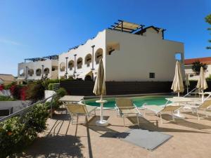 Una piscina con sillas y sombrillas frente a un edificio. en Zambrone Beach Villas, en Zambrone