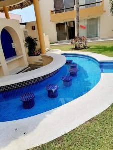 une piscine avec quatre tabourets devant une maison dans l'établissement VILLA ACAPULCO DIAMANTE, à Acapulco
