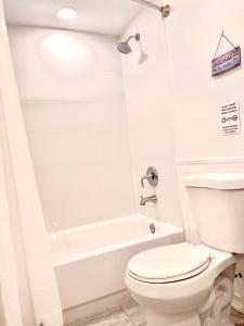 a white bathroom with a toilet and a tub at Classical Isbills Row House close to NYC in Bayonne