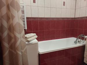 ein Badezimmer mit einer weißen Badewanne und roten Fliesen in der Unterkunft Однокімнатна біля автостанції, вулиця Зацепи in Luzk
