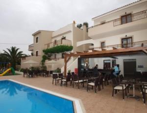 Ein Resort mit einem Pool, Tischen und Stühlen sowie einem Gebäude in der Unterkunft Asterion Apartments in Panormos