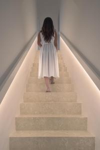 Une femme en robe blanche marchant par les escaliers dans l'établissement Casa Ruiz Suites, à Noto