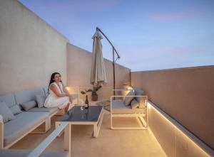 une femme assise sur un canapé sur un balcon dans l'établissement Casa Ruiz Suites, à Noto