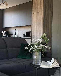 una sala de estar con sofá y un jarrón de flores sobre una mesa en MoonLight, en Slavske