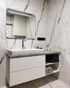 ein weißes Badezimmer mit einem Waschbecken und einem Spiegel in der Unterkunft MoonLight in Slawske