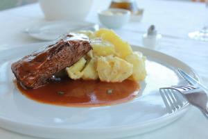 un plato de comida con carne y patatas en una mesa en Hotel Boutique Casa Werner, en Puerto Varas