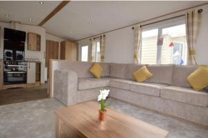 a living room with a gray couch and yellow pillows at Seaview Park Premium Static Caravan Whitstable in Whitstable