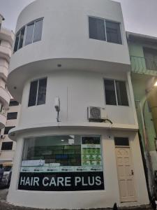 un edificio blanco con un cuidado de cabello y una señal en él en Resting View, en Male