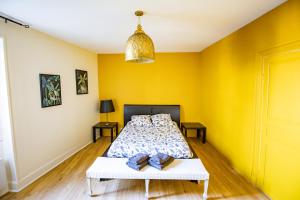1 dormitorio con paredes amarillas, 1 cama y 1 mesa en Chambres le Cèdre lezoux, en Lezoux