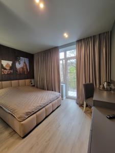 a bedroom with a bed and a desk and a window at Czernowitz Deluxe Apartments in Chernivtsi