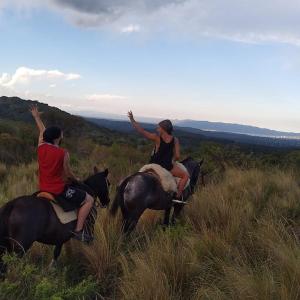 2 personnes à cheval sur une colline herbeuse dans l'établissement Don Alejandro, à Córdoba
