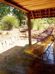 un banco amarillo sentado bajo un porche de madera en Camping Ojo de Agua en Nagarote