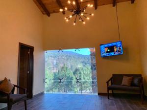 a living room with a tv and a large window at Cabaña No. 5 Puerta del Bosque Mazamitla. in Mazamitla