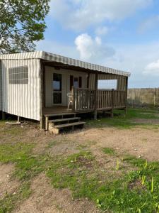 a small shed with a porch and stairs in a field at Mobil Home avec spacieuse terrasse à Meschers proche de Royan in Meschers-sur-Gironde