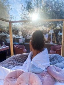 a woman laying on a bed looking out a window at Bubble Glamping Sicily in Catania